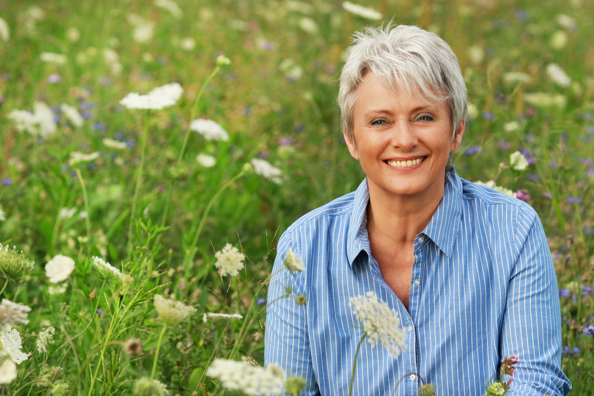 Happy attractive senior woman in a flowerfield